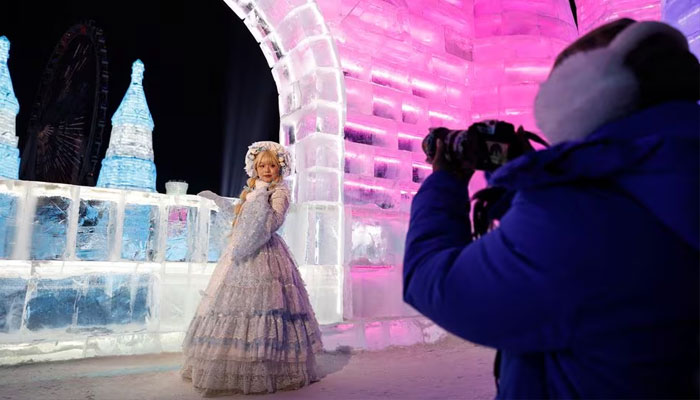 A woman dressed up in a costume poses for pictures in front of an ice sculpture depicting a castle, at the Harbin International Ice and Snow Festival, in Harbin, Heilongjiang province, China January 4, 2024.—Reuters