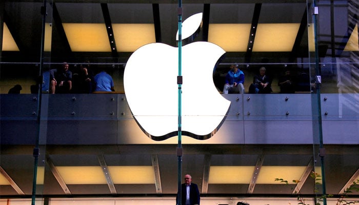 A customer stands underneath an illuminated Apple logo as he looks out the window of the Apple store located in central Sydney, Australia, May 28, 2018. — Reuters