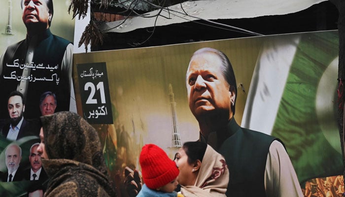 People walk past a banner of the Pakistan Muslim League Nawaz (PML N) party with an image of former prime minister of Pakistan and candidate Nawaz Sharif in Lahore on January 9, 2024, ahead of Pakistan´s upcoming general election. — AFP