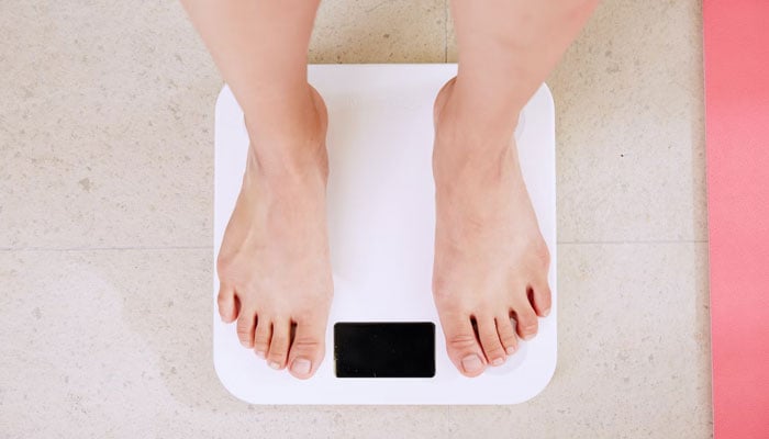 Image of a person standing on a weighing scale. — Unsplash/File
