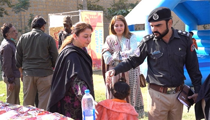 Sindh Inspector General (IG) Prisons Syed Munawar Shah’s wife Sakina Munawar (middle) and Deputy Inspector General (DIG) Sheba Shah (left) interact with a kid during the event in Karachi jail. — reporter
