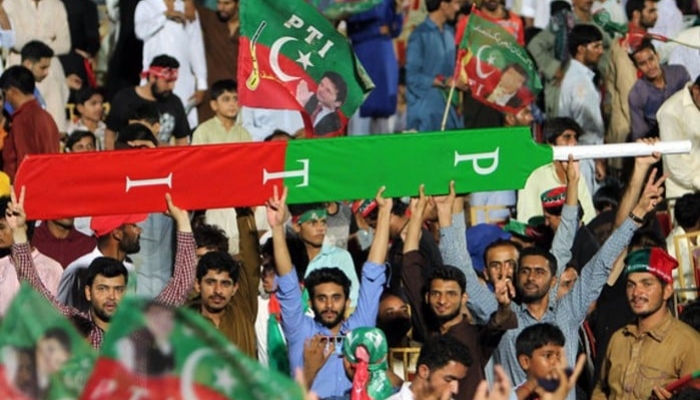 Supporters of former prime minister Imran Khan hold a giant cricket bat with the colours and initials of the party. —AFP/File