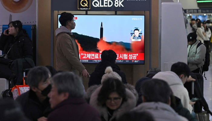 People watch a television screen showing a news broadcast with file footage of a North Korean missile test, at a railway station in Seoul on January 14, 2024. — AFP