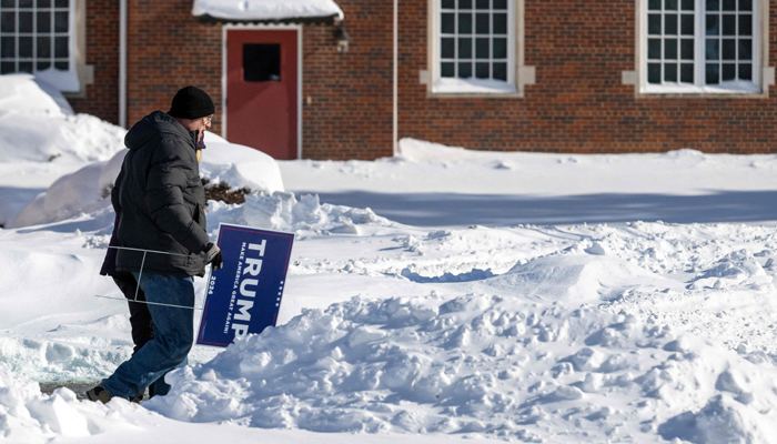 Supporters of former US President Donald Trump carry Trump placards as they brave the below-zero temperatures to attend a rally in Indianola, Iowa, on January 14, 2024. — AFP