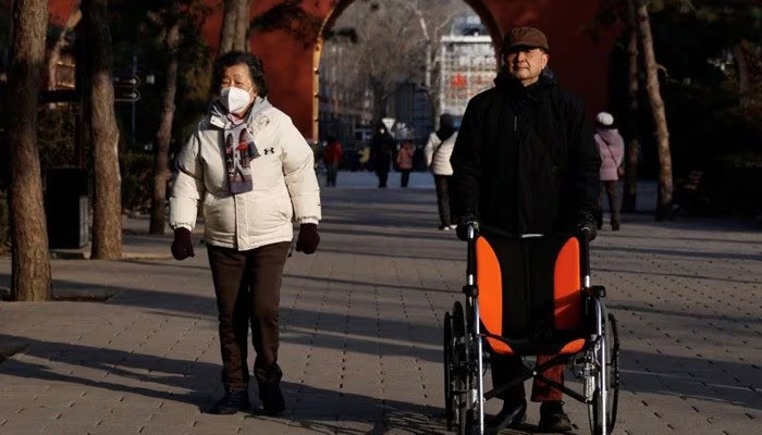An elderly man pushes a wheelchair as he walks at a park in Beijing, China January 16, 2024. —Reuters