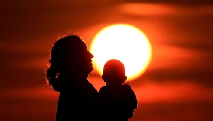 A mother and her baby enjoy the sunset on the beach in Calais, France, August 16, 2023. — Reuters