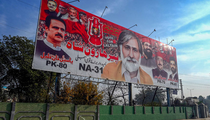 A car passes by an election billboard along a road in Peshawar on December 22, 2023, ahead of Pakistan´s general elections. — AFP