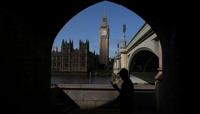 A man looks at his phone in view of the Palace of Westminster in London, Britain, September 22, 2023. —Reuters
