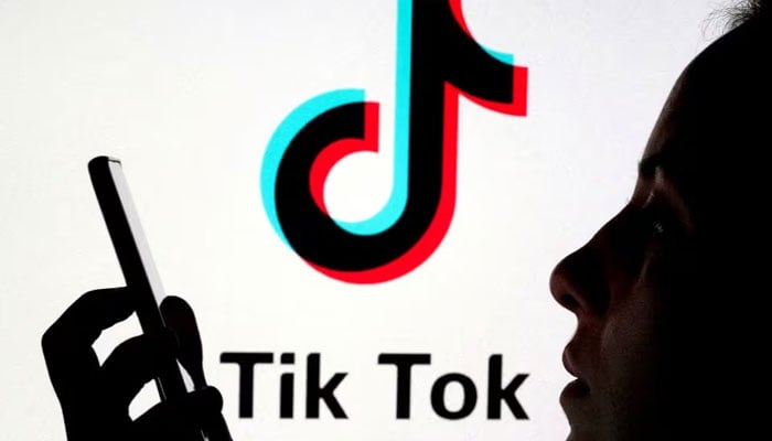A person holds a smartphone as Tik Tok logo is displayed behind in this picture illustration. — Reuters/File