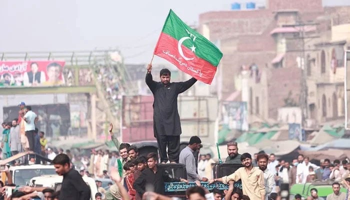 A PTI worker can be seen standing on a vehicle and waving the party flag in this image released on October 30, 2022. — Facebook/Imran Khan