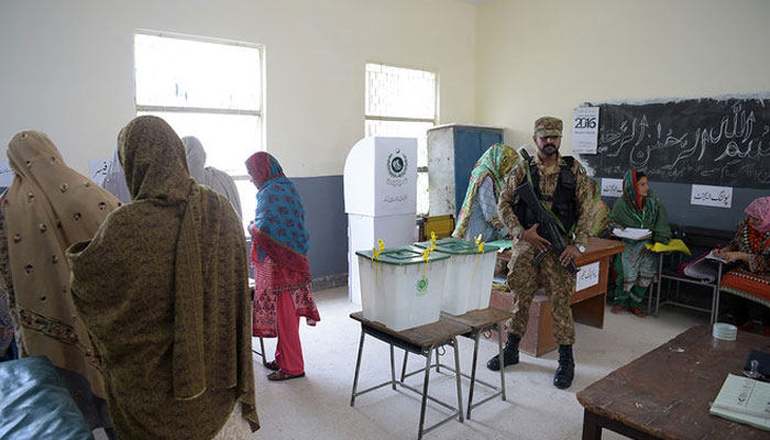 A Pakistani soldier stands guard next to ballot boxes during Pakistans general election at a polling station in Islamabad on July 25, 2018. — AFP