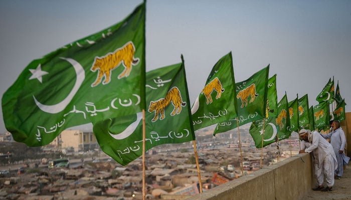 Workers install flags of PML-N on the rooftop of a building, ahead of the upcoming general elections, in Karachi on January 24, 2024. — AFP