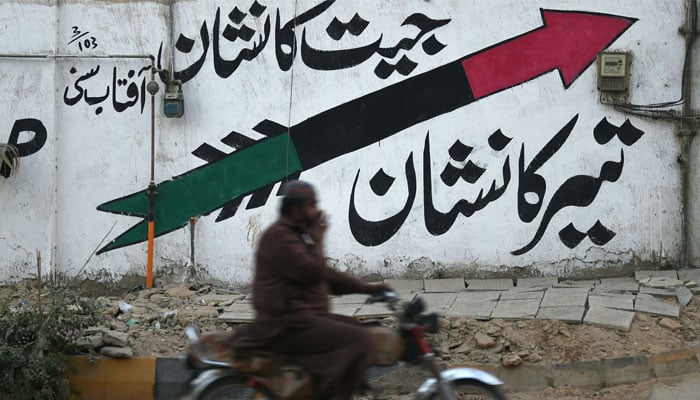 A motorcyclist rides past a wall painted with PPP logo along a street in Karachi on January 12, 2024, ahead of the upcoming general elections. — AFP