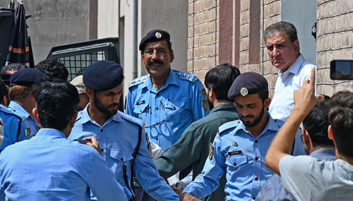 PTI leader Shah Mehmood Qureshi being escorted from a court premises after a hearing in this undated picture. — AFP/File