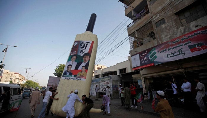 Supporters of Imran Khan, Pakistani cricketer-turned-politician and chairman of political party Pakistan Tehreek-e-Insaf (PTI), instal a giant bat symbol along a roadside in Karachi on May 4, 2013. — Reuters