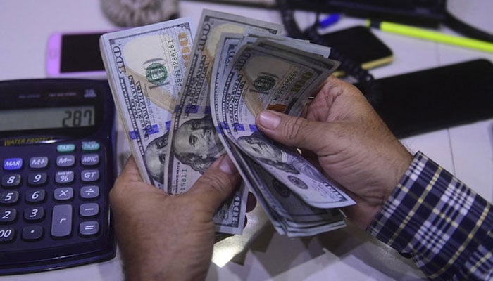 A dealer counts US dollars at a money exchange market in Karachi, Pakistan on March 2, 2023. — AFP