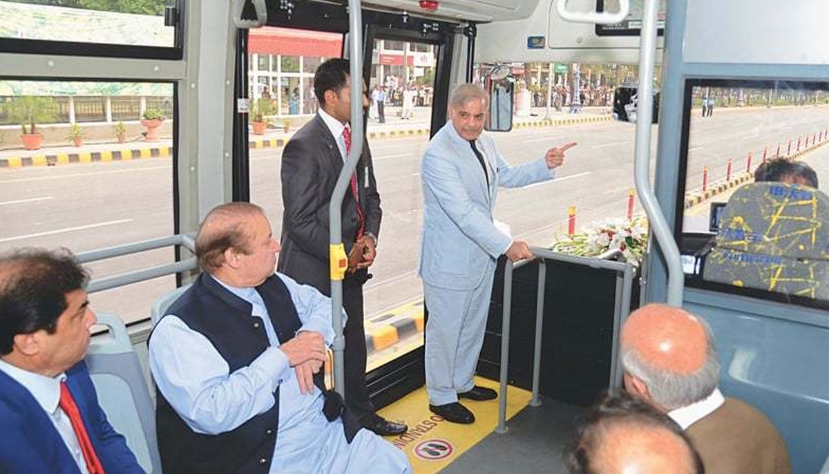 Nawaz Sharif, seated in a bus, being briefed on the route of the Metro Bus Service by Shehbaz Sharif. — PID