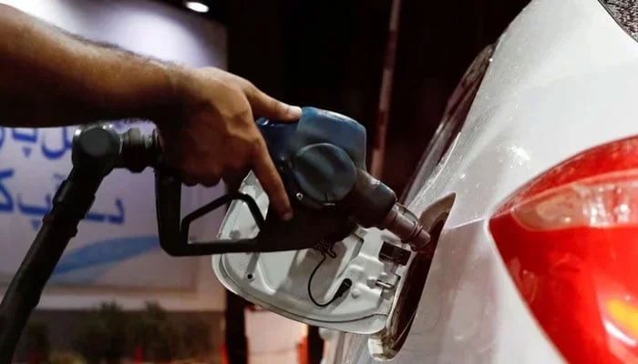 A worker holds a fuel nozzle to fills fuel in a car at petrol station in Karachi, on September 16, 2023. — Reuters