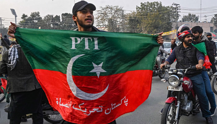 A supporter and activist of Pakistan Tehreek-e-Insaf (PTI) party hold party´s flag as he takes part in an election campaign rally in Lahore on January 28, 2024, ahead of the upcoming general elections. — AFP