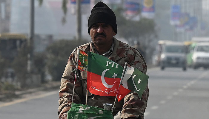 In this picture taken on January 17, 2024, a man rides a bicycle with flags of the Pakistan Tehreek-e-Insaf (PTI) party in Mianwali, the native town of Pakistans jailed former Prime Minister Imran Khan in Punjab Province. — AFP