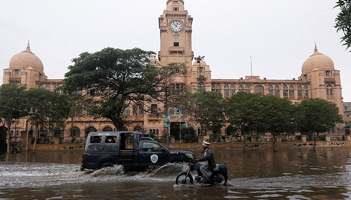 Vehicles drive through a flooded road in front of the Karachi Municipal Corporation (KMC) following a thunderstorm in the metropolis, on February 4, 2024. — Reuters