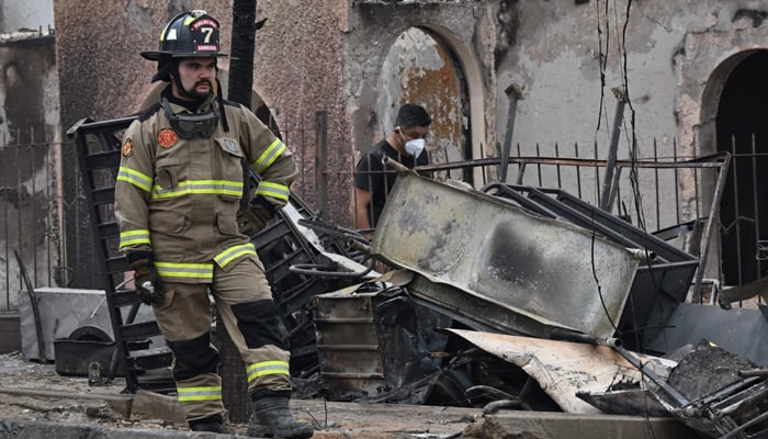 A firefighter rests next to burned houses after a forest fire in Viña del Mar, Chile, on February 4, 2024. — AFP