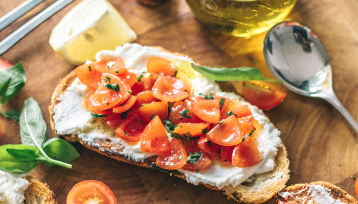 A tomato and cottage cheese toast with garnished herbs and olive oil. — Unsplash