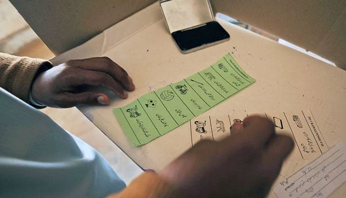 A man stamps on ballot papers as he casts his vote at a polling station in Chakri. — AFP/File