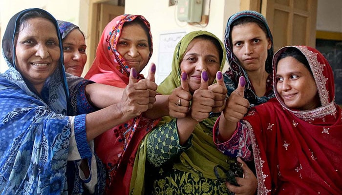 Voters displaying their marked thumbs after casting their ballots at a polling station in Qasimabad, Hyderabad. — APP/File