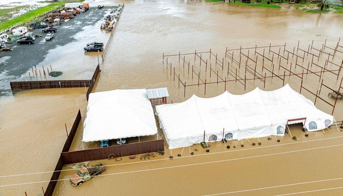 This aerial photograph shows vehicles and farm equipment flooded at the Mickelson Pumpkin Patch in Petaluma, California, on February 4, 2024. — AFP