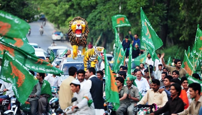 Supporters of Pakistan Muslim League-Nawaz (PML-N) march in a rally along with an effigy of a lion, the partys electoral symbol, on the top of a car for the general election in Islamabad on May 4, 2013. — AFP