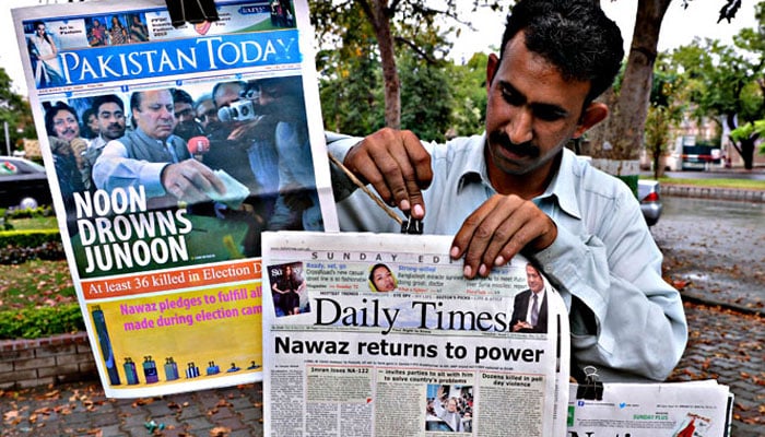 A Pakistani vendor arranges morning newspapers with front-page coverage of former Pakistani Prime Minister Nawaz Sharifs success in landmark elections the day before, along a roadside stall in Islamabad on May 12, 2013. — AFP
