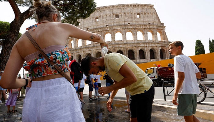 A woman pours water on a man near the Colosseum during a heatwave across Italy, in Rome, Italy, on July 18, 2023. — REUTERS/File