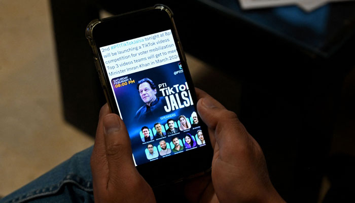 Pakistan´s former prime minister Imran Khan´s supporter listens to a virtual election campaign on a phone at Khan´s PTI office in Islamabad on February 3, 2024. — AFP