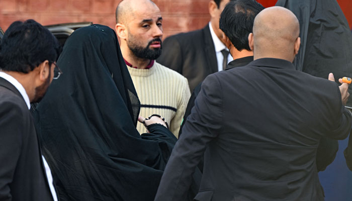 Security personnel escort Bushra Bibi (2L), wife of jailed former Pakistans Prime Minister Imran Khan, as she arrives at Adiala Jail in Rawalpindi on December 12, 2023, before hearing of her husband at a special court. — AFP