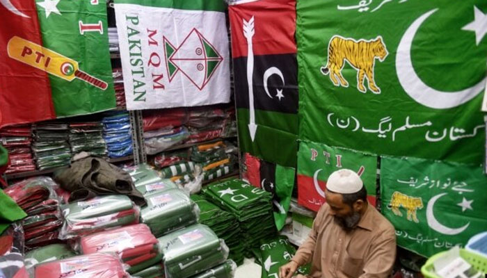 A shopkeeper arranges flags of political parties at his shop ahead of the upcoming general elections in Karachi. — AFP/File