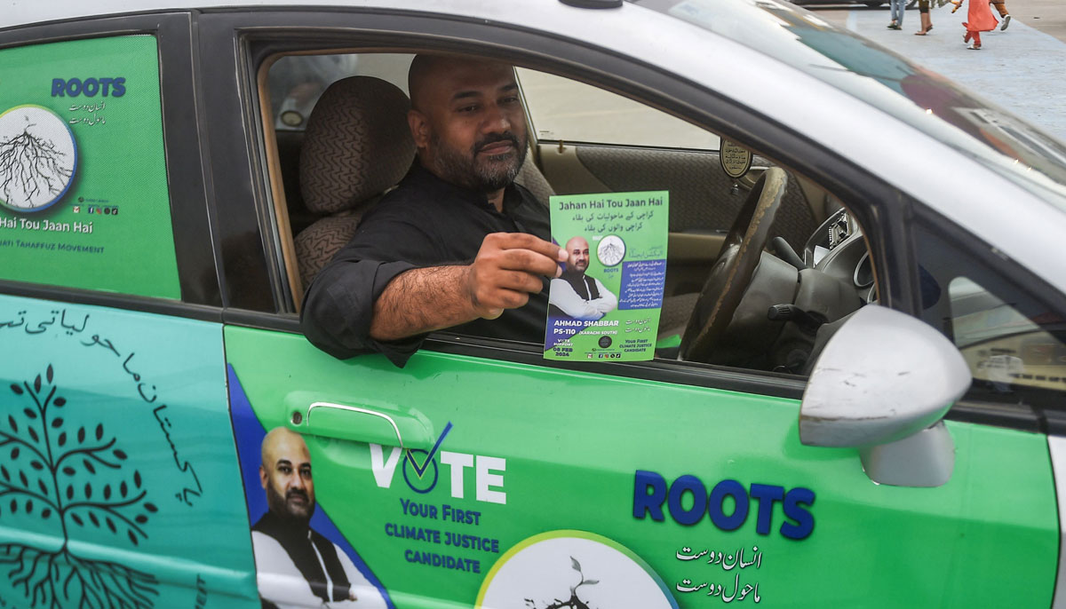 This photo taken on February 3, 2024, shows Ahmad Shabbar, independent election candidate and founder of the Pakistan Maholiati Tahaffuz Movement, showing his pamphlet from his car at a campaign event to raise awareness on climate threats in Karachi. — AFP