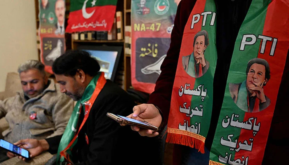 Former prime minister Imran Khans supporters wear scarves with prints of his Pakistan Tehreek-e-Insaf party as they listen to a virtual election campaign on phones at a party office in Islamabad on February 3, 2024. — AFP