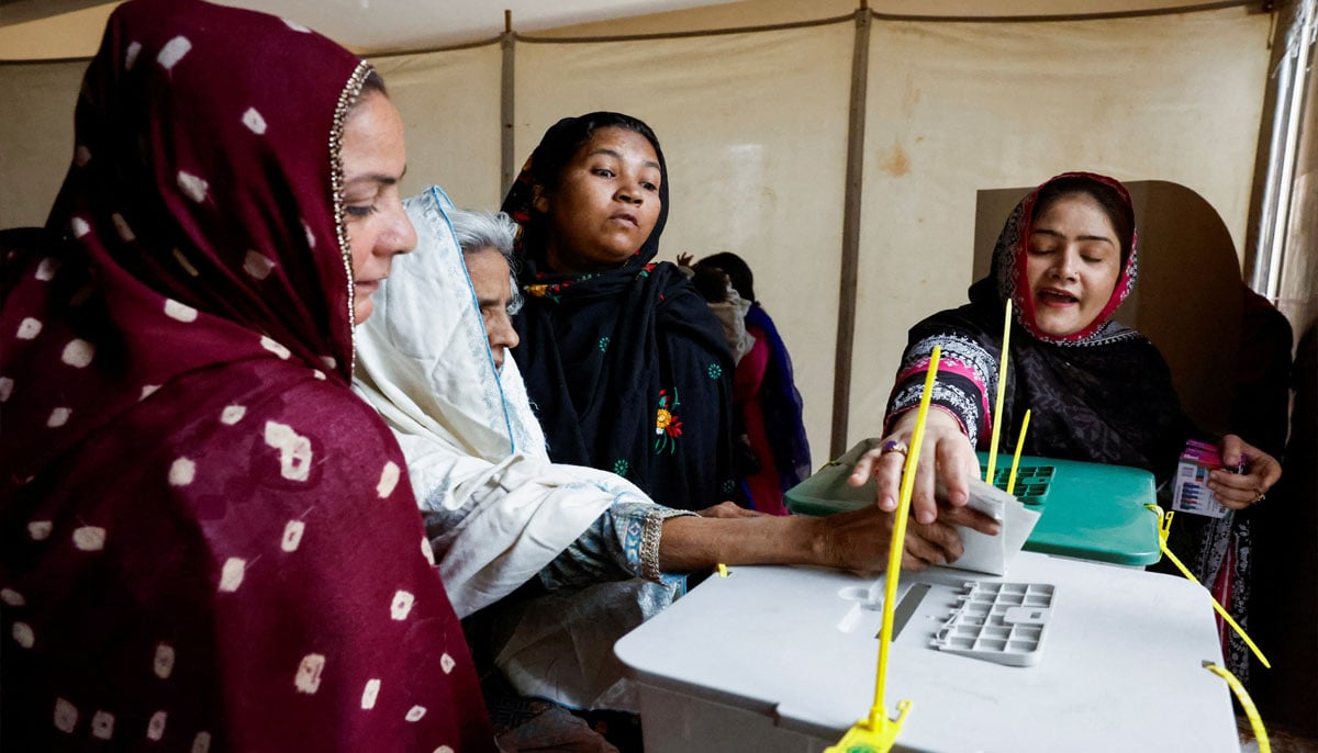 Women volunteers help Sughra Bibi, 93, as she arrives to cast a vote during the general election in Karachi, Pakistan February 8, 2024.