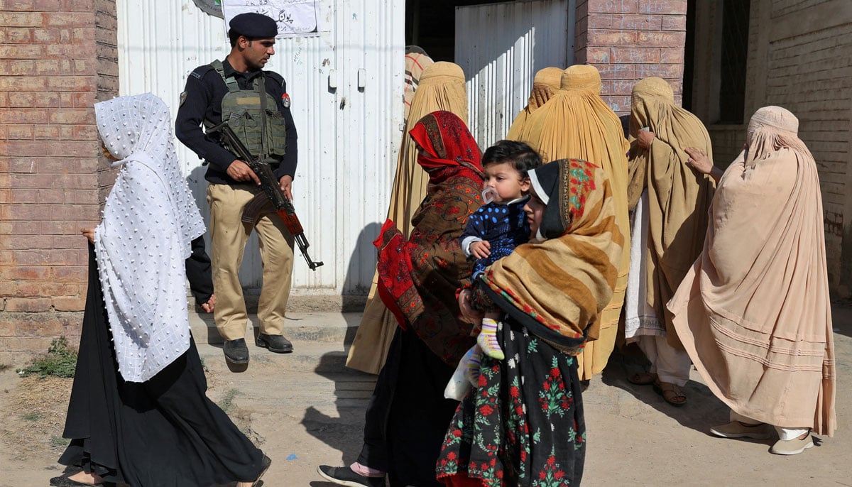 Women arrive at a polling station to cast their vote as a police officer stands guard during general election, in Peshawar, Pakistan, February 8, 2024. — Reuters