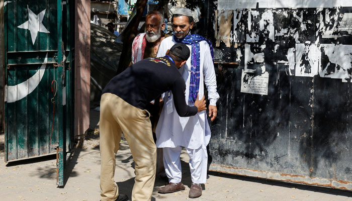 A police officer frisks a voter at the entrance of a polling station during the general election in Karachi, Pakistan February 8, 2024. — Reuters