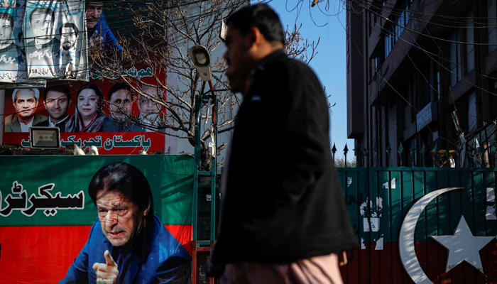People walk past a banner with a picture of the former prime minister Imran Khan outside the party office of Pakistan Tehreek-e-Insaf (PTI), a day after the general election, in Lahore, February 9, 2024. — Reuters