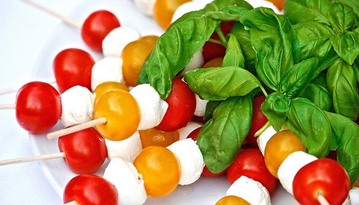 A plate of Caprese Salad Kebabs with cherry tomatoes and cheese. — Pixabay