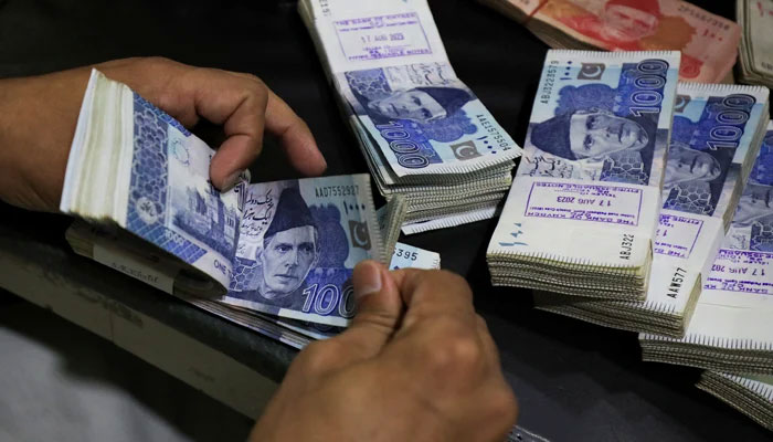 An employee counts Pakistani rupee notes at a bank in Peshawar, on August 22, 2023. — Reuters