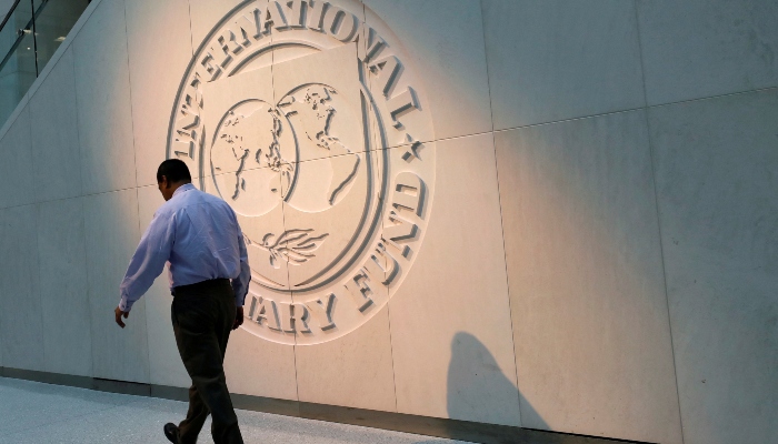 A man walks past the International Monetary Fund (IMF) logo at its headquarters in Washington, US, on May 10, 2018. —Reuters