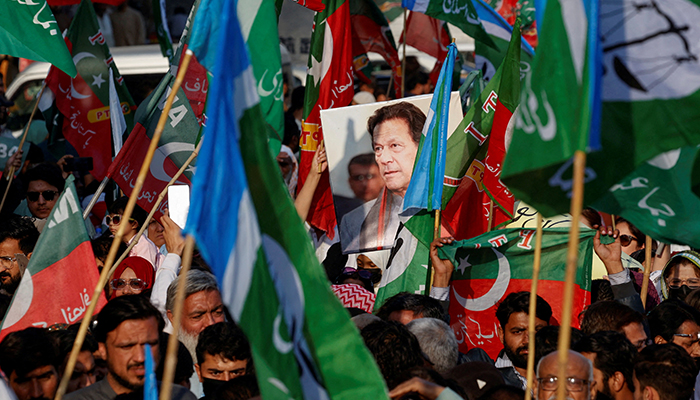 A portrait of PTI founder Imran Khan is seen amid flags of PTI and JI as supporters attend a joint protest demanding free and fair results of the elections, outside the provincial ECPin Karachi, on February 10, 2024. — Reuters