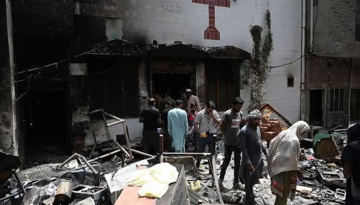 Police officials and residents stand amid debris outside the torched Saint John Church in Jaranwala on the outskirts of Faisalabad on August 17, 2023. — AFP