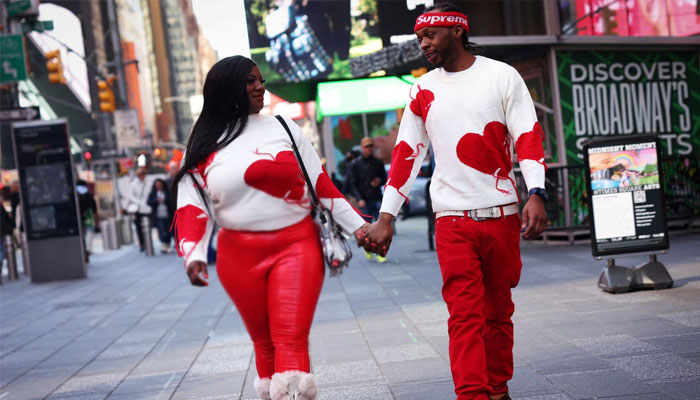 A couple in matching heart themed sweaters walk hand in hand through Times Square on Valentines Day in New York City. —Reuters