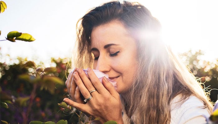 A woman smells a flower. — Unsplash