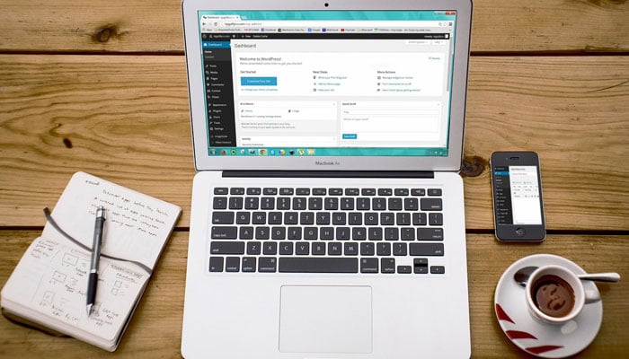 The image shows a notebook, a laptop, and a mobile phone. — Pixabay